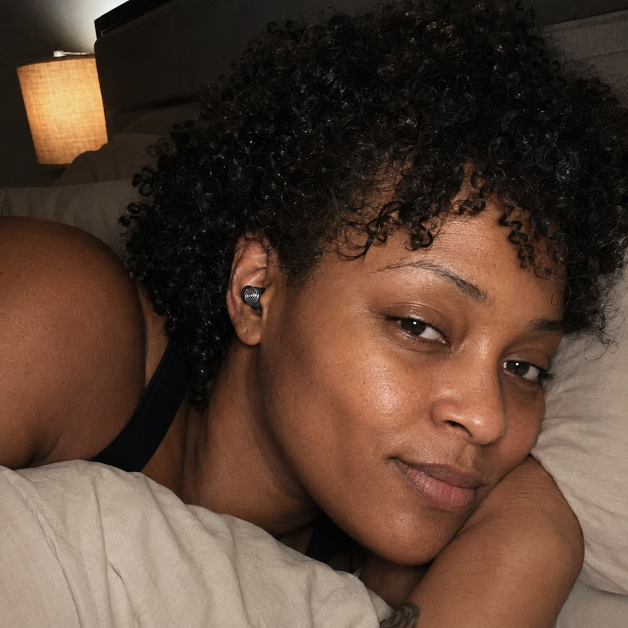 Customer resting in bed while wearing a Driftwell earplug